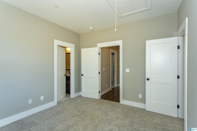 unfurnished bedroom with ensuite bath, carpet, attic access, and baseboards