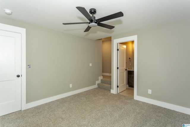 unfurnished bedroom featuring light carpet, ceiling fan, ensuite bathroom, and baseboards