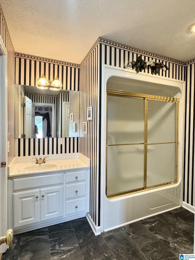 bathroom featuring vanity, combined bath / shower with glass door, and a textured ceiling