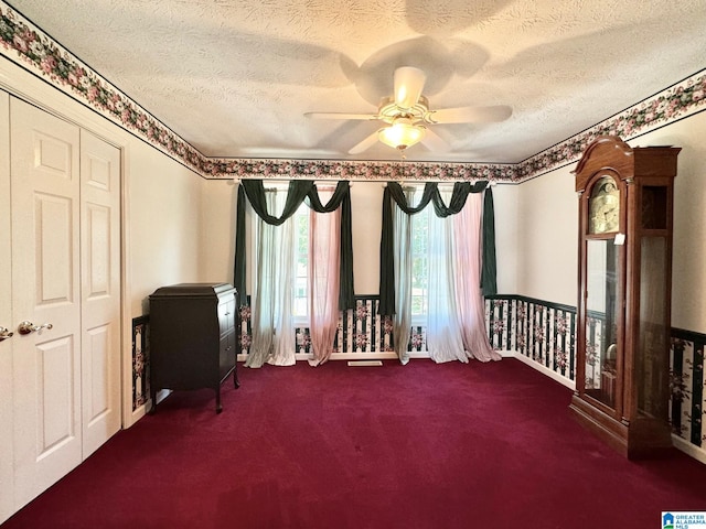 miscellaneous room with ceiling fan, dark carpet, and a textured ceiling