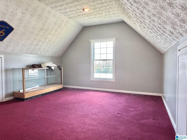 bonus room featuring a textured ceiling, carpet floors, and lofted ceiling