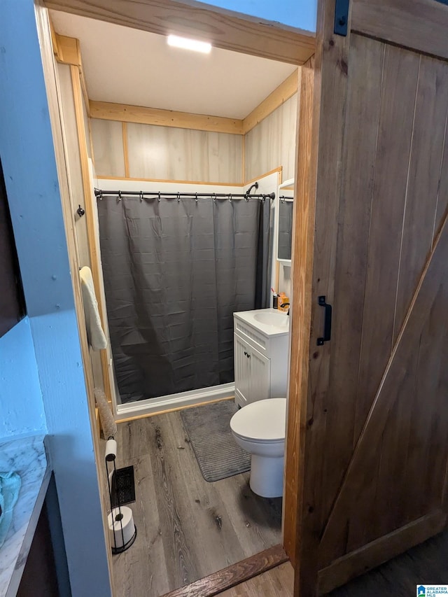 bathroom with a shower with shower curtain, wood-type flooring, vanity, and toilet