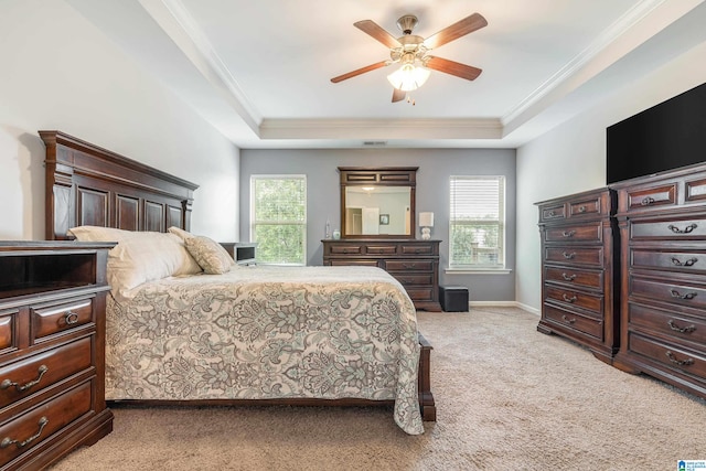 carpeted bedroom with ceiling fan, a raised ceiling, and crown molding