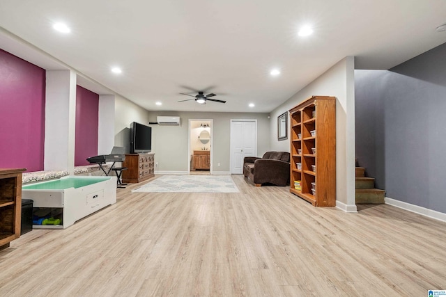 living room featuring a wall mounted air conditioner, light hardwood / wood-style flooring, and ceiling fan