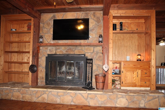 details with a fireplace, beamed ceiling, wood ceiling, and ceiling fan