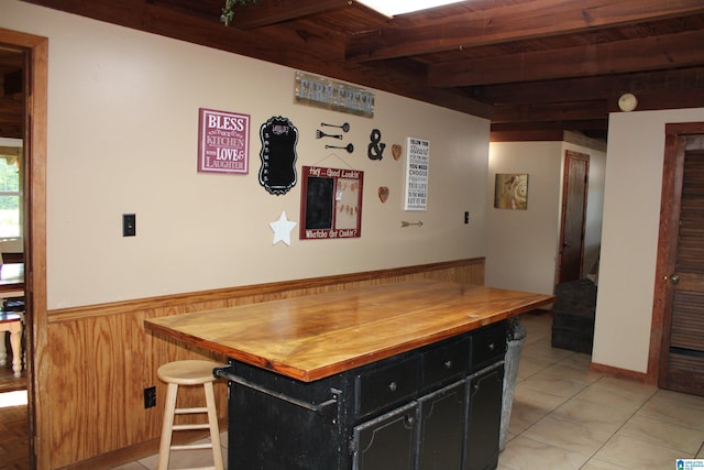 kitchen featuring wooden ceiling, beam ceiling, light tile patterned floors, and wooden counters