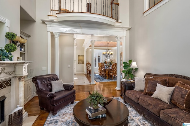 living room with decorative columns, a towering ceiling, and light hardwood / wood-style flooring