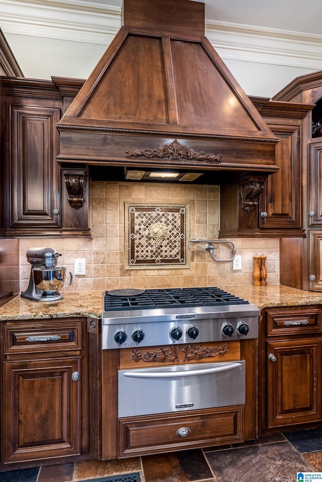 kitchen with light stone counters, tasteful backsplash, stainless steel gas stovetop, and custom range hood