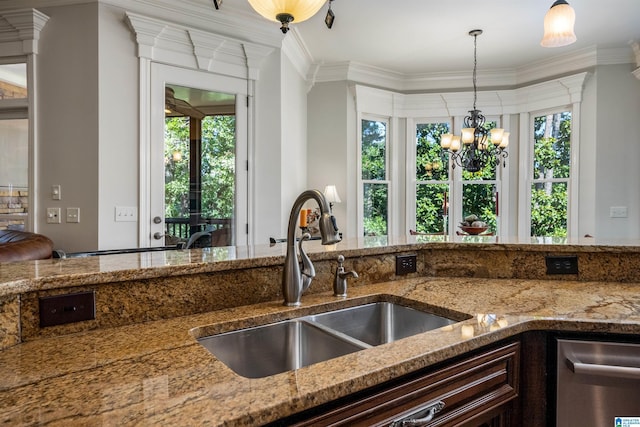 kitchen featuring pendant lighting, sink, crown molding, and stone counters