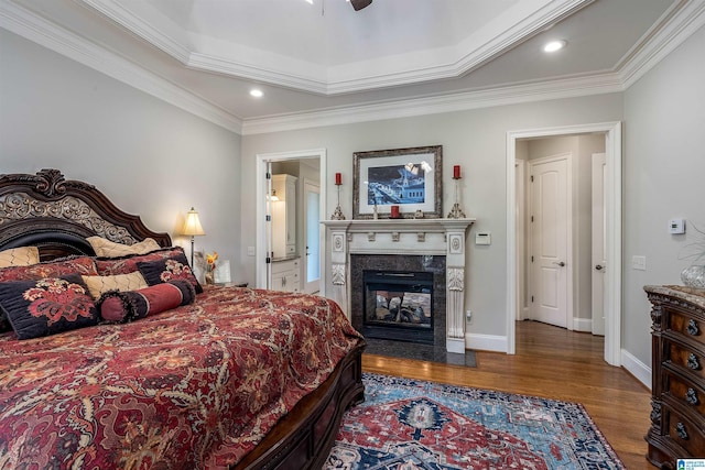 bedroom with crown molding, ceiling fan, a premium fireplace, and dark hardwood / wood-style flooring