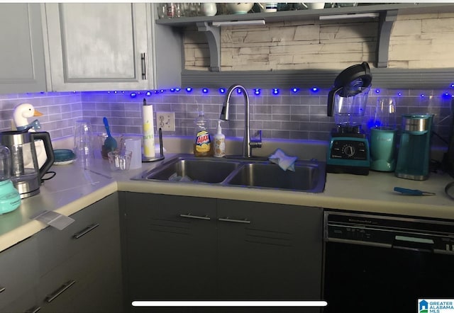 kitchen featuring black dishwasher, sink, white cabinets, and backsplash