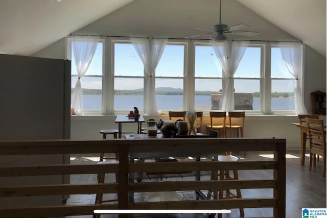 dining area with a water view, ceiling fan, vaulted ceiling, and a wealth of natural light