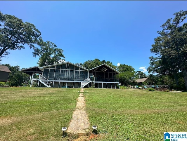 rear view of property featuring a lawn and a sunroom