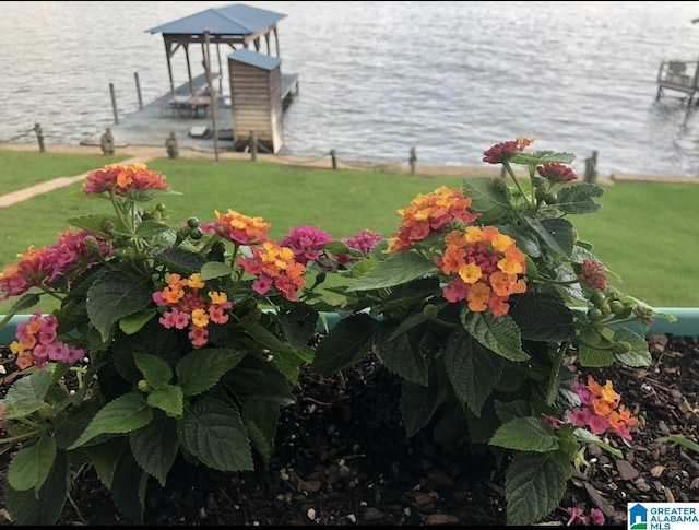 view of dock with a lawn and a water view