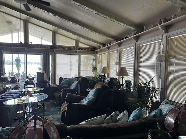 living room with ceiling fan, lofted ceiling with beams, and a textured ceiling