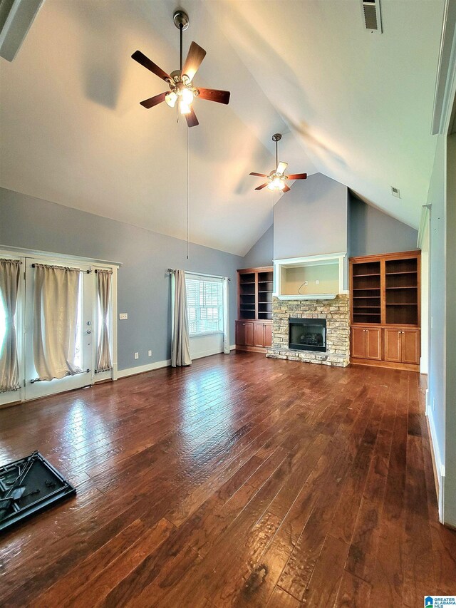 unfurnished living room featuring ceiling fan, dark wood-type flooring, a stone fireplace, and lofted ceiling