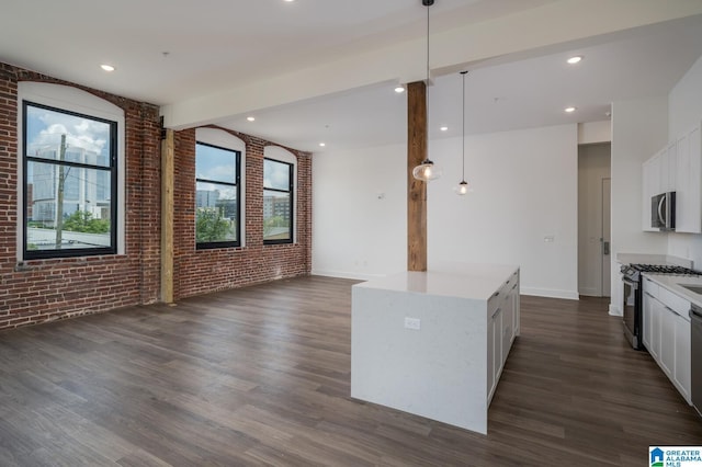 kitchen featuring decorative light fixtures, brick wall, white cabinets, and stainless steel appliances