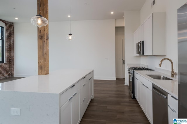 kitchen with pendant lighting, appliances with stainless steel finishes, dark wood-type flooring, white cabinetry, and sink