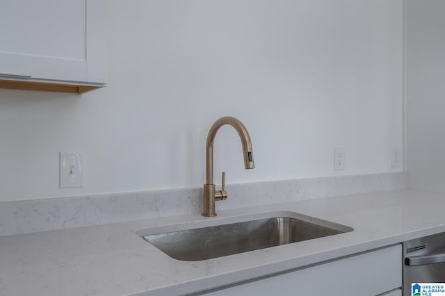 interior details with light stone countertops, white cabinetry, and sink