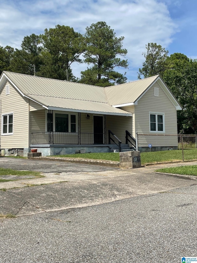 view of front of property with a porch, metal roof, fence, and driveway