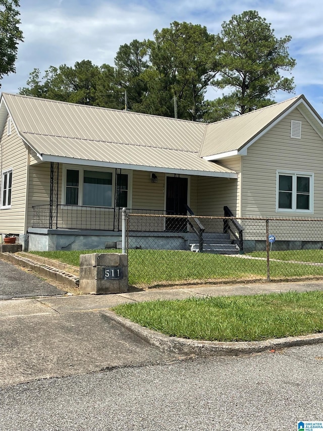 view of front of house with a porch, metal roof, and a fenced front yard