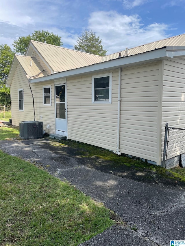rear view of property with central AC unit and metal roof