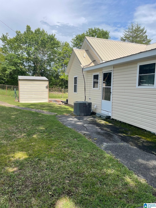 back of property with a storage shed, an outbuilding, central air condition unit, and metal roof