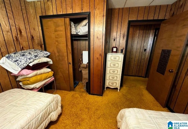 bedroom featuring a closet, wooden walls, and carpet