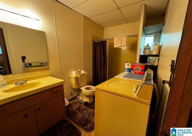 bathroom featuring toilet, vanity, curtained shower, washer / clothes dryer, and a drop ceiling