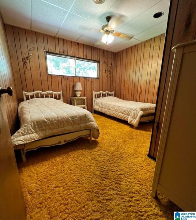 bedroom with wood walls, ceiling fan, and carpet flooring