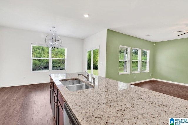 kitchen with decorative light fixtures, a chandelier, sink, light stone countertops, and dark wood-type flooring