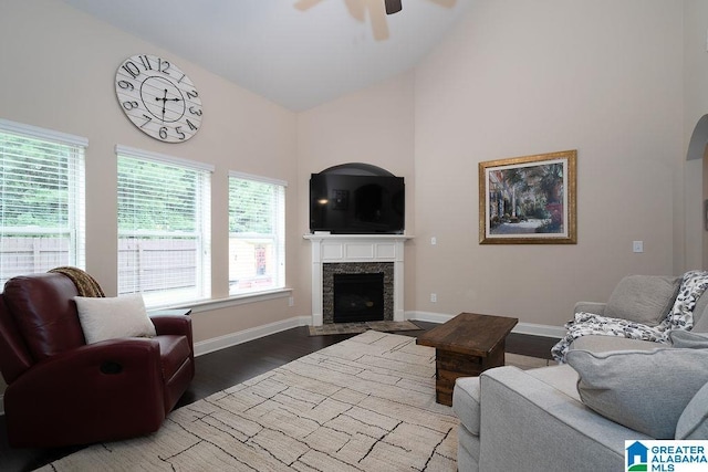 living room featuring ceiling fan, high vaulted ceiling, a fireplace, and wood-type flooring