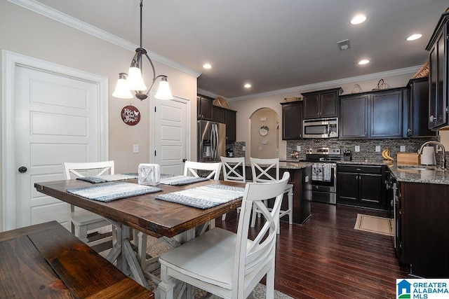 dining space with an inviting chandelier, crown molding, dark hardwood / wood-style flooring, and sink