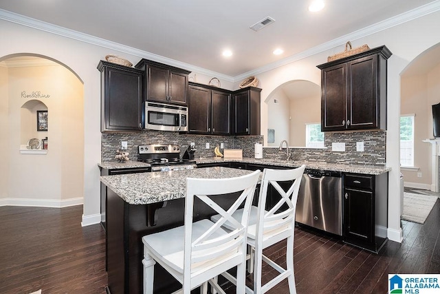 kitchen with stainless steel appliances, crown molding, and a kitchen island