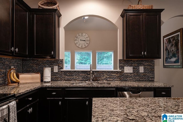 kitchen featuring sink, stainless steel dishwasher, backsplash, and light stone countertops