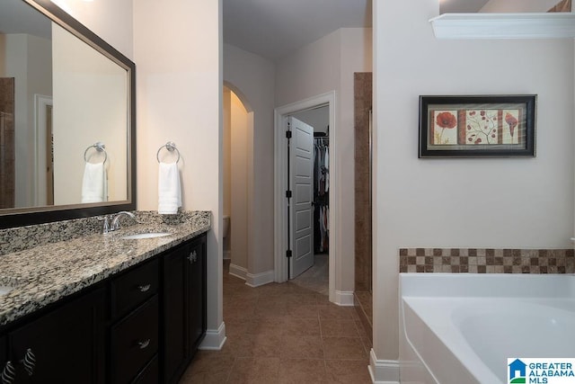 bathroom featuring toilet, tile patterned floors, a tub to relax in, and vanity