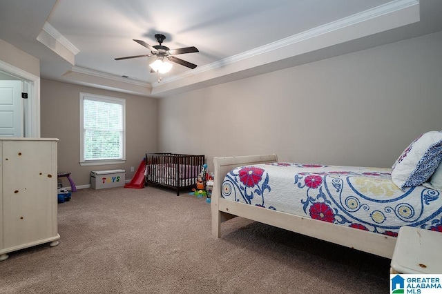 carpeted bedroom with a raised ceiling, ceiling fan, and crown molding