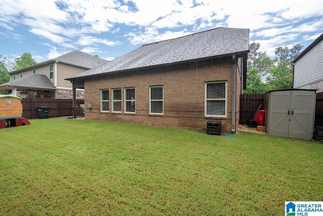 rear view of house featuring a lawn and a storage shed