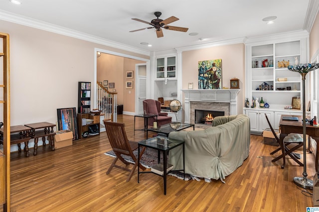 living area featuring wood finished floors, a high end fireplace, a ceiling fan, stairs, and ornamental molding