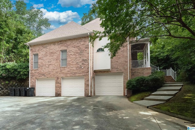 view of side of home with a shingled roof, concrete driveway, brick siding, and an attached garage