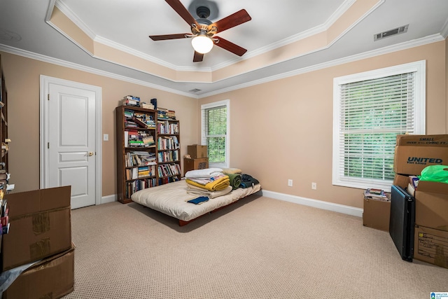 carpeted bedroom with baseboards, visible vents, a ceiling fan, ornamental molding, and a tray ceiling