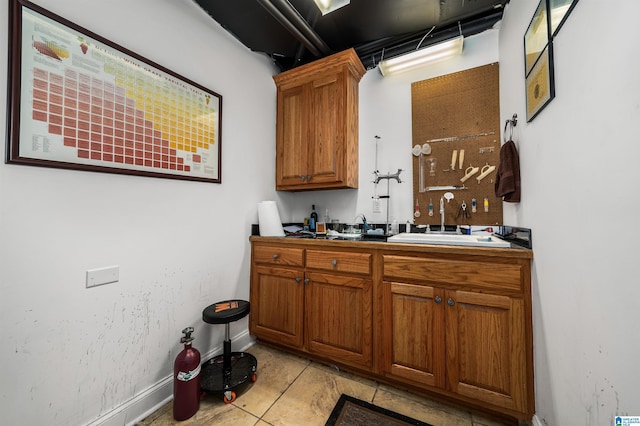 kitchen with baseboards, brown cabinets, and a sink