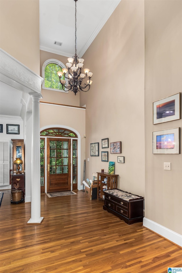 foyer entrance with ornamental molding, wood finished floors, and decorative columns