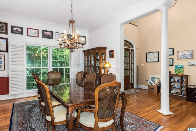 dining area featuring decorative columns, ornamental molding, wood finished floors, a chandelier, and baseboards