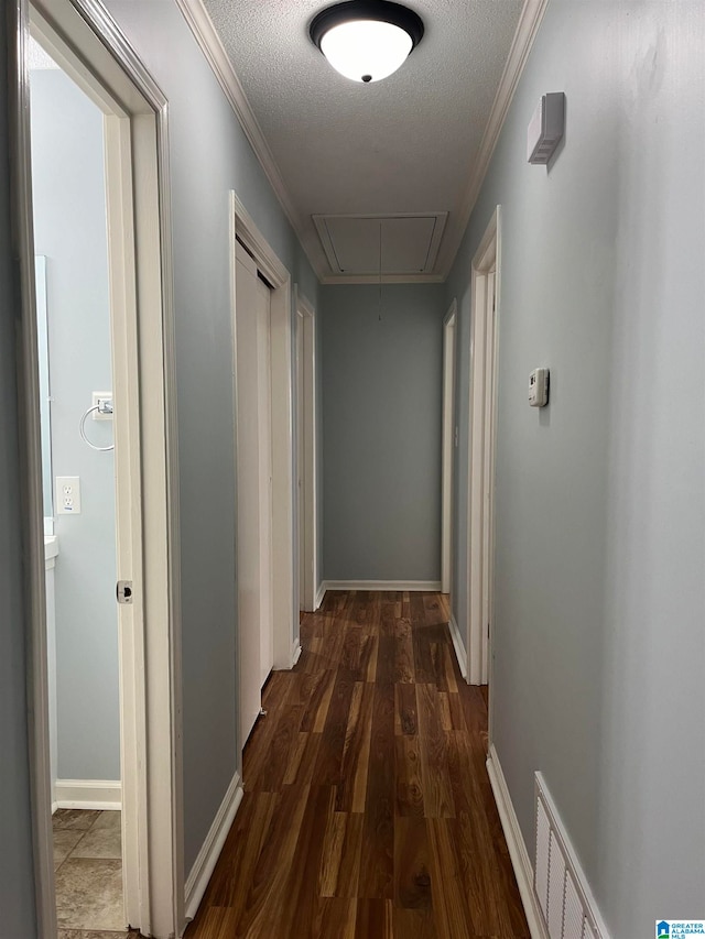 hallway with dark wood-type flooring, a textured ceiling, and crown molding