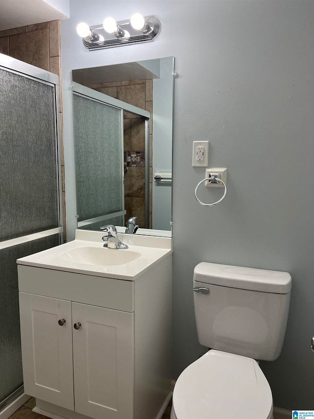 bathroom featuring toilet, vanity, and an enclosed shower