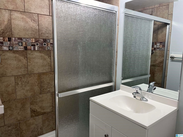 bathroom featuring a shower with shower door and vanity