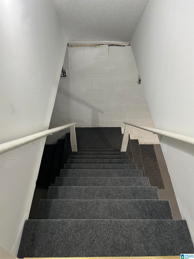 stairs featuring a textured ceiling