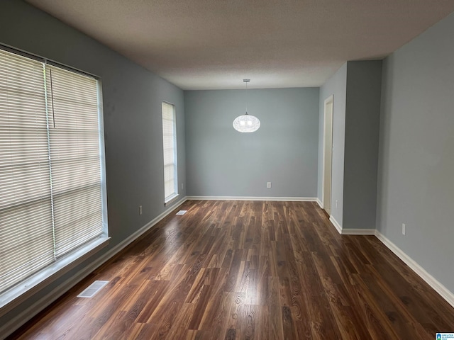 empty room with dark hardwood / wood-style flooring and plenty of natural light