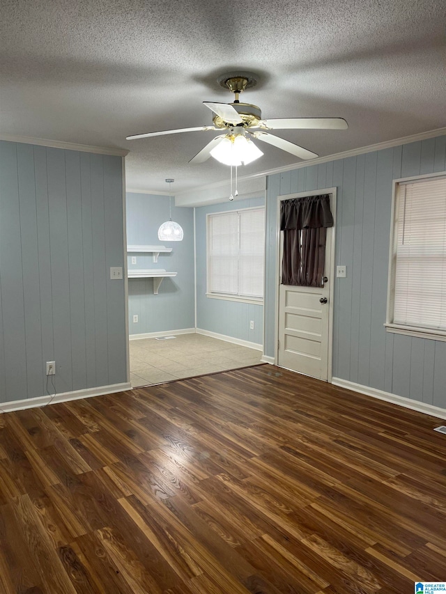 interior space with a textured ceiling, dark hardwood / wood-style flooring, wooden walls, and ceiling fan